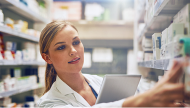 A pharmacist reaching for medication on a pharmacy shelf